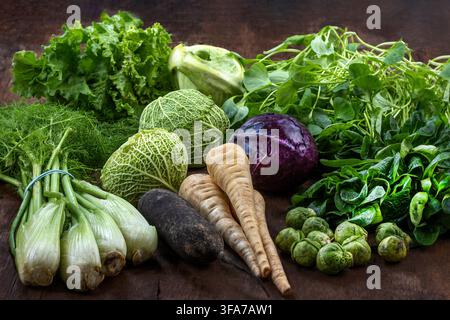Various fresh vegetables are arranged on a dark wooden surface. Stock Photo