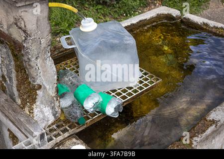 A metal rack placed over a water-filled container, with a large plastic jug and several plastic bottles on it. Stock Photo