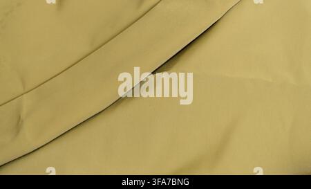 Minimalist olive green fabric background featuring a single prominent diagonal crease crossing the smooth textile surface. The elegantly draped materi Stock Photo