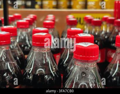 Close up of plastic bottle necks with red caps filled with dark soda drink on a store shelf. High quality photo Stock Photo