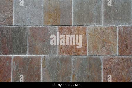 Horizontal close-up view of a multicolor square brick wall with variegated bricks and smooth even mortar joints showing visible surface details Stock Photo