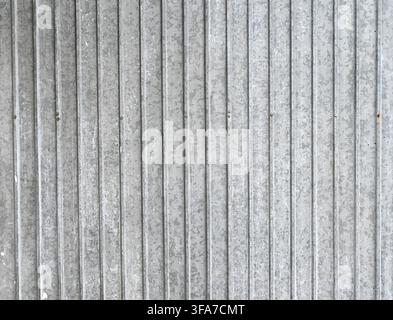 Horizontal close up view of a weathered corrugated galvanized metal surface with vertical ridges and white mineral deposits along with paint splatters Stock Photo