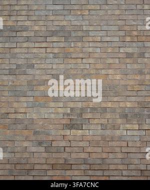 Vertical close-up view of a multi toned light brown brick wall surface with porous, rough, uneven bricks and smooth porous mortar joints Stock Photo