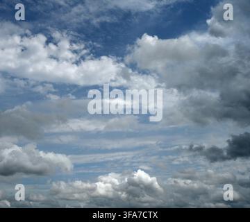 Horizontal close up of a mostly cloudy sky with light and dark clouds, larger cloud formations and smaller scattered clouds Stock Photo