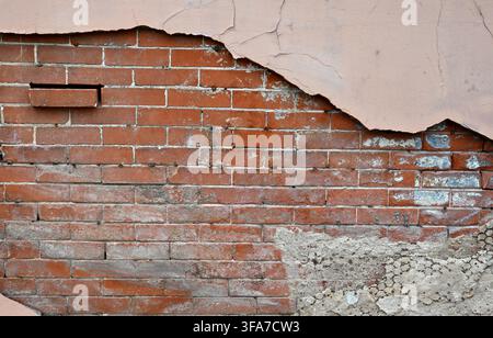 Horizontal close-up view of a deteriorating multi-layer wall surface with tan painted concrete pulling away Stock Photo