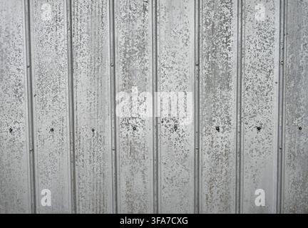 Horizontal close-up view of weathered corrugated tin metal with a silver galvanized surface and small rust areas Stock Photo