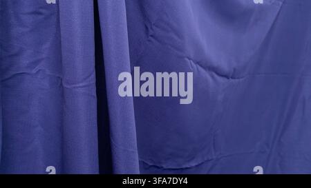A rich dark blue cloth is beautifully displayed with distinct vertical drapes on the left side, transitioning into a softer, flatter surface towards t Stock Photo