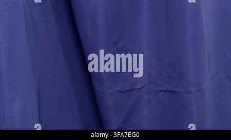 A luxurious dark blue textile is elegantly draped to form deep shadowed crevices and soft overlapping waves. The smooth surface of the fine cloth inte Stock Photo