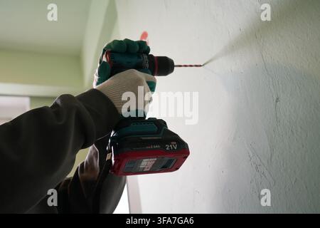 Low angle of hands using brushless cordless drill on wall Stock Photo