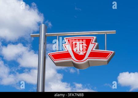 A red and white exterior sign featuring the Toronto Transit Commission (TTC) logo against a blue sky with white clouds, Stock Photo