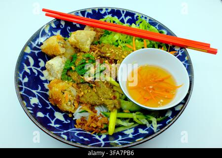 Asian kitchen. Bo Bun. Vietnamese bowl with fried spring rolls, beef, aromatic herbs, and vibrant fresh vegetables. Stock Photo