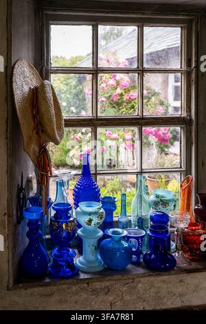 Straw hat and blue glassware on windowsill in greenhouse of Georgian home in the Scottish borders, UK. Stock Photo