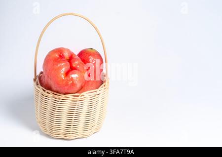 Two Wet Rose Apples in a Small Woven Basket on a White Background Stock Photo