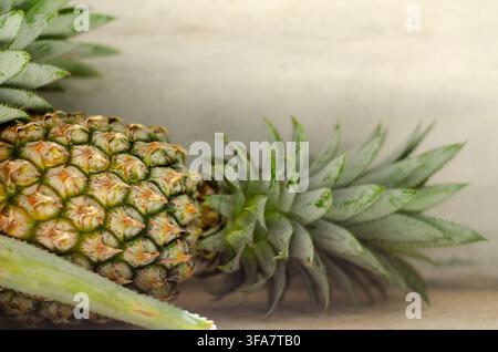 Pineapples with Textured Skin and Leafy Green Tops on a Neutral Surface Stock Photo