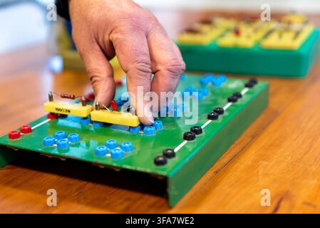 Technician Hands Assembling Electronic Circuit Components on Training Breadboard in Electronics Workshop Stock Photo
