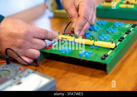 Technician Hands Assembling Electronic Circuit Components on Training Breadboard in Electronics Workshop Stock Photo