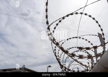 Coiled Razor Wire Fence Against Overcast Sky Low Angle View Stock Photo