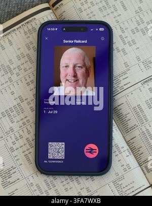 UK digital Senior Railcard displayed on a smartphone app over a train timetable,used to plan discounted rail journeys for travellers aged 60 and over. Stock Photo