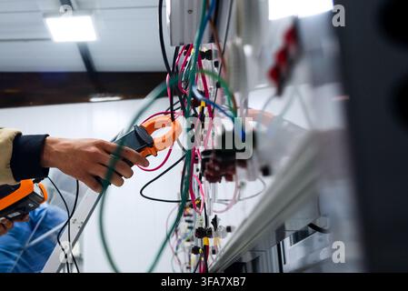 echnician using a clamp meter to measure electrical current in a solar training system. Stock Photo