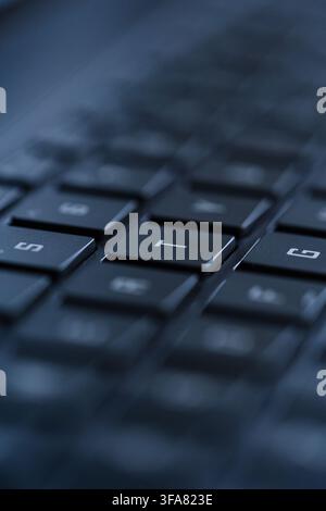 Macro view of black laptop keyboard keys with shallow depth of field and blue lighting Stock Photo