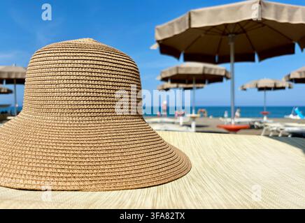 Close up of a woven straw hat on a sunbed with a blurred beach background. Concept of summer vacation, relaxation, sun protection, travel. Copy space Stock Photo