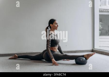 Woman practicing full front split on a mat at home, mindful flexibility and mobility training for active longevity, body awareness, functional fitness Stock Photo