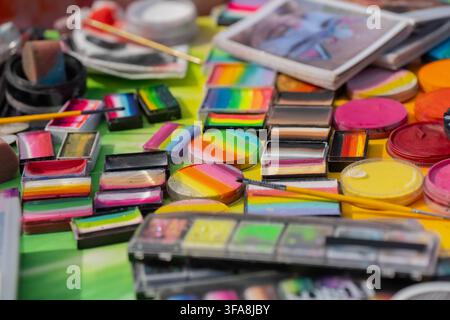 Vibrant rainbow split cake face paint containers and fine art brushes arranged on artist workstation for festival face painting and creative makeup ar Stock Photo