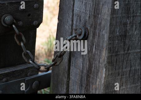 Close-up view of a metal chain securing a wooden gate to a wooden post Stock Photo