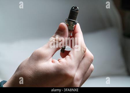 Close up of hand holding worn spark plug, automotive maintenance and repair concept Stock Photo
