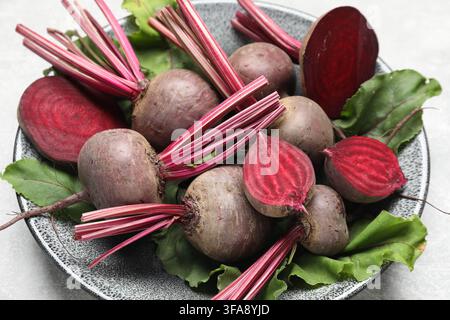 Whole and cut young beets with green leaves on table, closeup Stock Photo