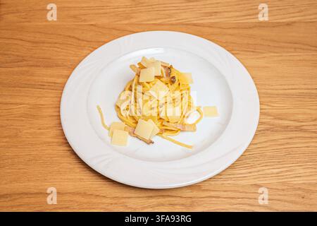 Spaghetti Carbonara Twirled with Crispy Pancetta and Topped with Shaved Pecorino Cheese Slices Stock Photo