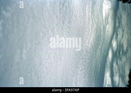 Expansive altocumulus cloud layer with textured ripple patterns fills the frame, creating a dramatic atmospheric mood with soft blue-gray tones. Stock Photo