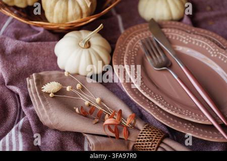 A fall tablescape with white pumpkins, textured plates, a ribbed glass goblet, and a soft linen napkin, creating a warm and rustic atmosphere for seas Stock Photo