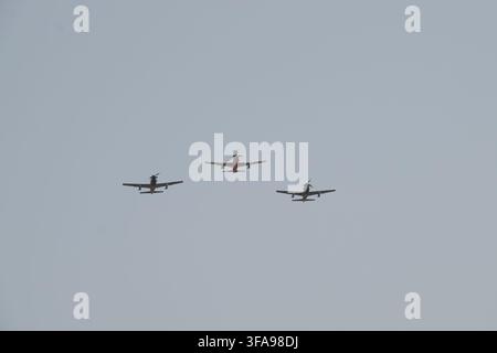 Three propeller planes flying together in formation against a clear sky Stock Photo