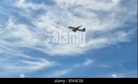 Commercial passenger airliner flying high in a bright blue sky Stock Photo