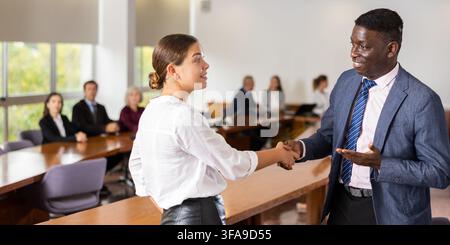 Middle aged african male manager welcoming a new white female employee Stock Photo