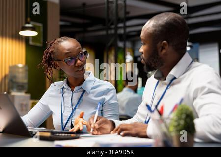 Teaching intern, laptop and manager in office managing company meetings schedule. Doing internship, notebook and team leader with trainee compiling computerized company information records Stock Photo