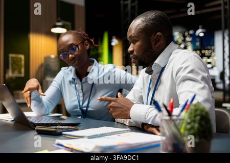 Manager in office teaching intern to manage company meetings schedule on laptop. Team leader and trainee doing internship compiling computerized company information records with notebook Stock Photo