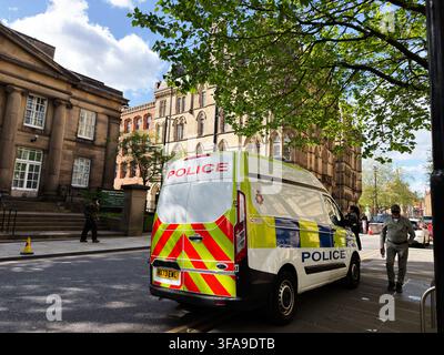 Manchester, UK - May 10, 2026: Police van parked on a sunny Manchester, UK street beside historic Victorian buildings and pedestrians. Stock Photo
