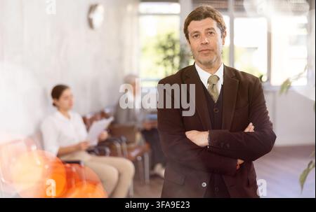 Confident businessman standing with arms crossed in lobby of office Stock Photo