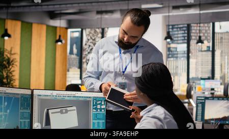 Team of engineers brainstorm upgrades for innovative solar powered device prototype. Research and development office coworkers do trial of portable solar panel gadget to improve efficiency, camera B Stock Photo