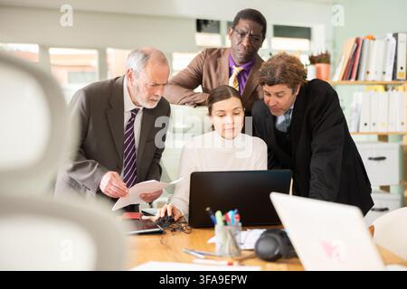 Group of businessmen working together, looking at a laptop and discussing issues Stock Photo