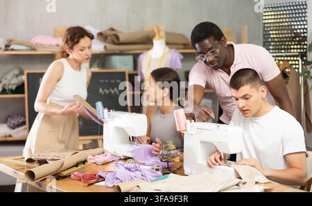 Sewing teacher helping student with machine threading in workshop Stock Photo