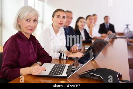 Senior woman manager using laptop during conference Stock Photo