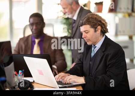 European man working on laptop with room in office Stock Photo
