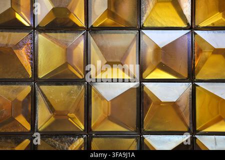 Golden glass squares creating a textured, reflective surface with geometric patterns Stock Photo