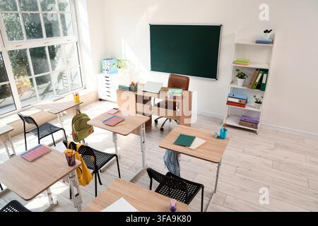 Modern empty classroom interior, back to school and education concept, bright learning environment with desks and chalkboard Stock Photo