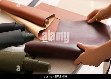 Craft and design materials, hands selecting faux leather fabric rolls for upholstery and fashion projects Stock Photo