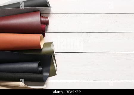 Leather craft and upholstery materials, rolls of colorful faux leather fabric on a white wooden background with copy space Stock Photo
