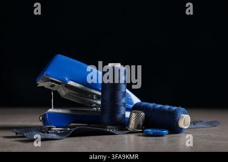 Manual sewing machine with tailors supplies on grunge grey table against black background Stock Photo